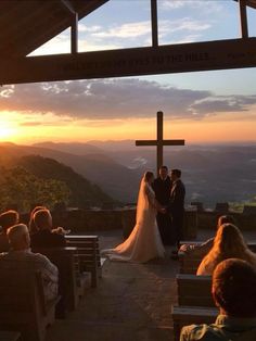 a bride and groom standing at the alter during their wedding ceremony with sunset behind them