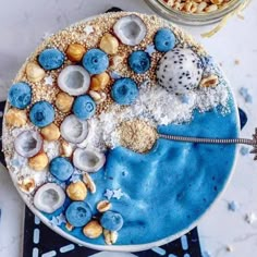 a cake with blue icing and nuts on it sitting next to a bowl of cereal