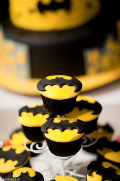 cupcakes decorated with black and yellow icing are arranged in the shape of batman's