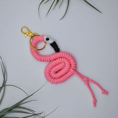 a flamingo keychain made out of pink rope with a black and white handle