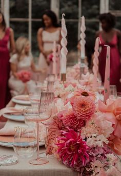 the table is set with pink flowers, candles and wine glasses for an elegant wedding reception