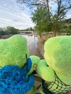 two teddy bears sitting next to each other on a boat in the water and one is wearing a blue scarf