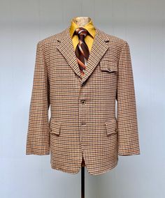 * Traditional half Norfolk jacket c 1970s  * 100% wool * Brown and rust houndstooth on a beige background  * Wide, notched lapel  * Single breast flap pocket * Double hip flap pockets  * Back features action pleats at shoulders, a sewn half-belt and a long single vent * Three button closure * Pale blue rayon lining features 3 welted pockets * Shirt and tie are shown for styling purposes and are not included. * Tie is available for purchase here:  https://www.etsy.com/listing/1808826323/vintage-1 Retro Wool Sport Coat For Workwear, Retro Wool Sport Coat For Tailoring, Retro Wool Tweed Jacket For Work, Retro Wool Sport Coat With Notch Lapel, Retro Fall Sport Coat With Welt Pockets, Retro Sport Coat With Welt Pockets For Fall, Retro Tweed Outerwear For Business, Vintage Notch Lapel Sport Coat For Fall, Retro Wool Sport Coat With Welt Pockets