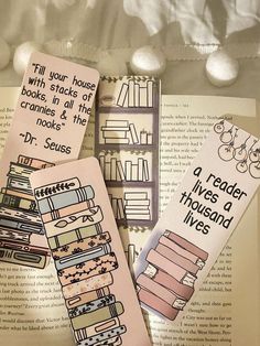 three bookmarks that are sitting on top of an open bookshelf with words written in them