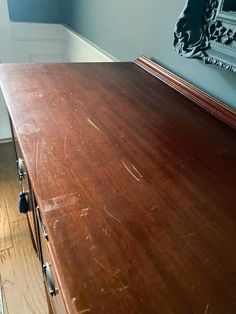 an old wooden table in a room with blue walls and wood flooring on the side