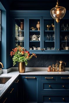 a kitchen with blue cabinets and marble counter tops, gold vases on the island