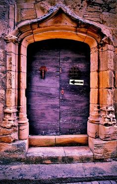 an old wooden door with iron bars on the front and side, surrounded by stone pillars