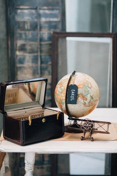 an old fashioned suitcase sitting on top of a table next to a small model airplane