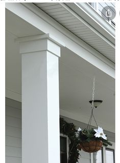 the porch is decorated for christmas with white flowers and greenery hanging from it's posts