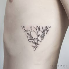 a small tree branch tattoo on the back of a woman's left shoulder