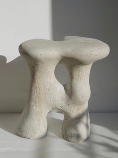 a white sculpture sitting on top of a table next to a shadow cast wall behind it