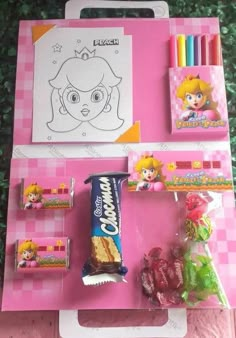 a pink table topped with lots of candy and candies next to a drawing board