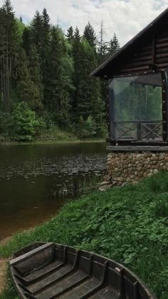 there is a small boat sitting on the grass next to a building with a glass window