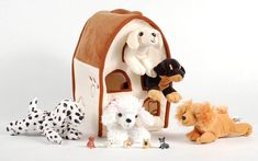 several stuffed animals are shown in front of a small dog house with two puppies