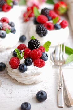 berries, raspberries and blueberries on top of meringue with mint leaves