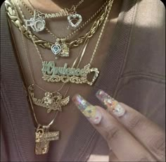 a woman holding onto some necklaces with charms on it's neck and hands