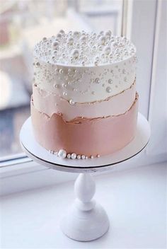 a three layer cake sitting on top of a white plate next to a window sill