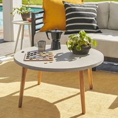 a coffee table sitting on top of a rug next to a couch and potted plant