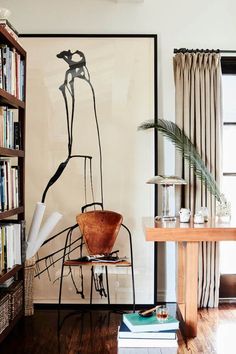 a living room with bookshelves and a painting on the wall in front of it