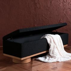 a black box with a white blanket on top of it sitting on a wooden floor