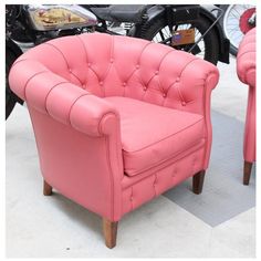 a pink leather chair sitting on top of a white tile floor next to a motorcycle