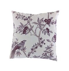 a white and purple pillow with a bird on the tree branch in front of it