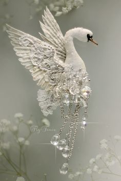 a white swan with wings and jewels on its body is floating in water surrounded by flowers