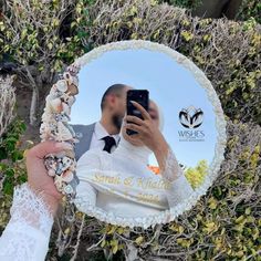 a man and woman taking a selfie in front of a mirror with seashells on it