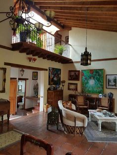 a living room filled with lots of furniture under a wooden beamed ceiling over a tiled floor