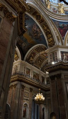 the interior of an ornate building with chandeliers and paintings on the ceiling,