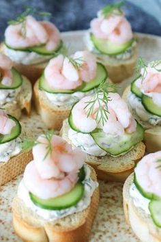 small sandwiches with shrimp and cucumbers on them are arranged on a platter