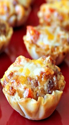 several mini pizzas sitting on top of a red table