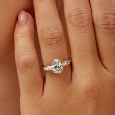 a woman's hand with a diamond ring on top of her finger and an engagement band