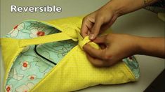 a person is sewing on a yellow bag with the words reversible written above it