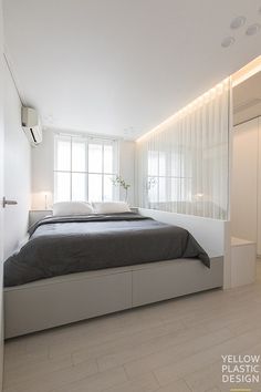 a bed sitting in the middle of a bedroom next to a white dresser and window