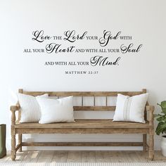 a wooden bench sitting in front of a wall with a bible verse on it's side