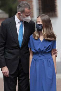 a man in a suit and tie standing next to a woman wearing a face mask