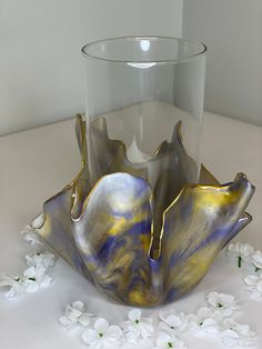 a glass vase sitting on top of a table with white flowers around it and an artistic design in the middle