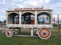 an old fashioned cart with wheels on display in the grass at a fair or carnival