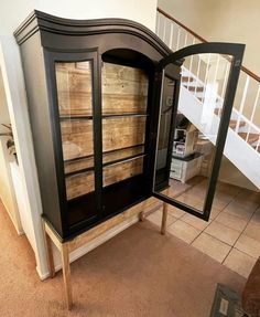 a wooden cabinet sitting on top of a carpeted floor next to a stair case