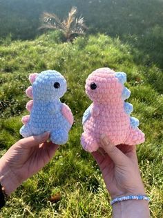 two handmade stuffed animals are held in front of the camera, with grass and palm trees behind them