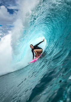 a woman riding a wave on top of a surfboard