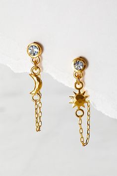 Just as effortless as they are eye-catching, these stunning earrings feature blue topaz- the stone of communication, wisdom and love- anchored to a gleaming sun and moon by a delicate gold chain. * Sun - vitality, leadership, life. * Moon - nourishment, protection, goddess * Blue topaz - communication, wisdom, love * Stone size - 4.5mm round faceted * Sun pendant size - 6mm * Moon pendant size - 6 x 3mm * Chain length - 1 1/4'' * 18kt gold plate over brass | Satya Jewelry Promise Of Magic Earrin Magic Earrings, Satya Jewelry, Delicate Gold Chain, Goddess Jewelry, Sun Pendant, Bold Jewelry, Mismatched Earrings, Celestial Jewelry, Fall Jewelry