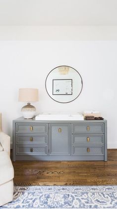 a white couch sitting next to a dresser on top of a hard wood floor