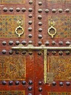 an old wooden door with metal knobs and decorative designs on the doors, which are decorated