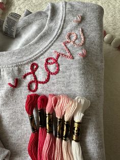 some yarn and crochet hooks are laying on a sweater that says sew