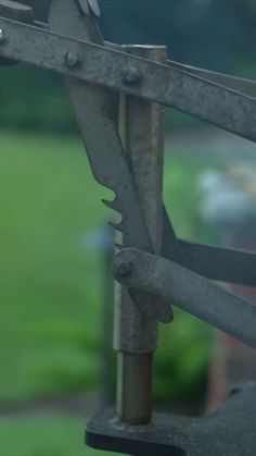 an old pair of scissors hanging off the side of a metal structure with grass in the background