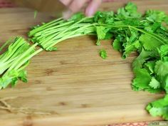 a person cutting up some green vegetables on a wooden board