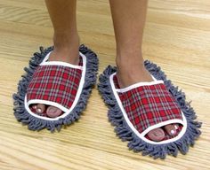 a pair of feet wearing slippers on top of a wooden floor next to a blue mop