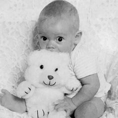 a baby is holding a teddy bear in his arms